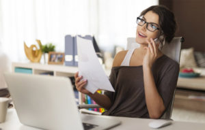businesswoman talking on phone in front of laptop